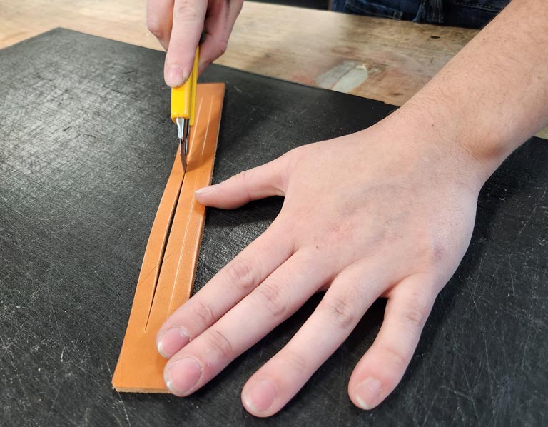 Cutting leather strands to be braided.