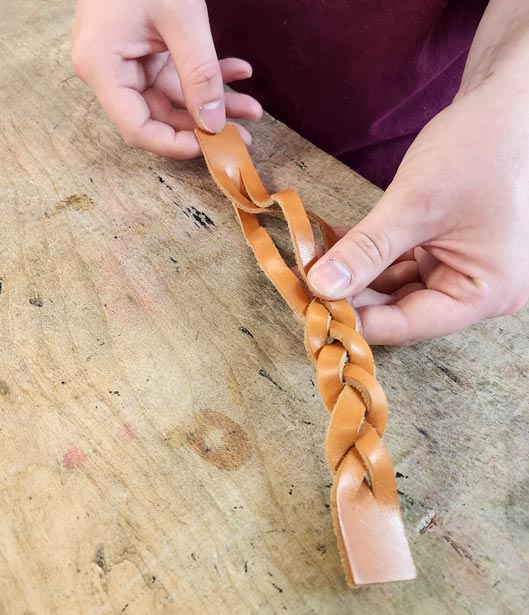 Finishing the leather braiding sequence.