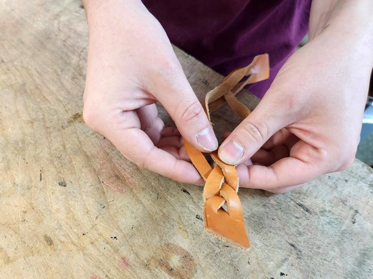 Weaving the three leather strands.